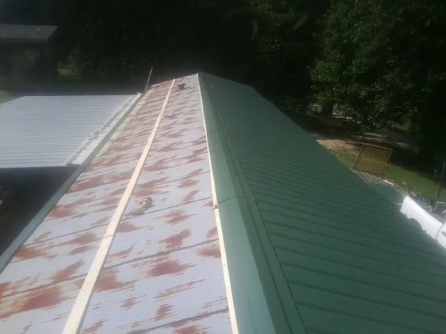 Old rusted panels beside newly installed green metal roofing — Wind Damage Roof Repair by Roofing Brothers in Green Bay