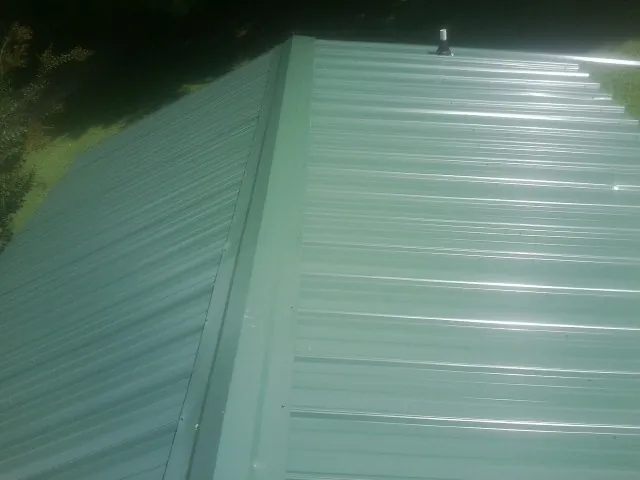 New green metal panels meeting at the ridge of a roof — Flat Roof Repair work by our crew in Green Bay