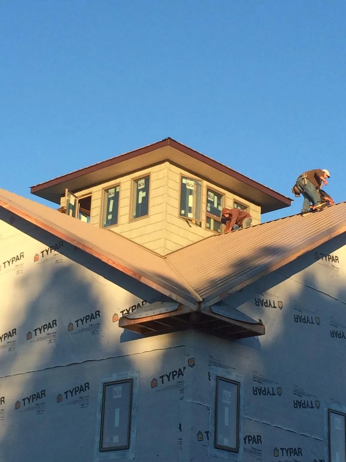 Roofers working around a rooftop cupola on a new metal roof at sunset — Roof Waterproofing in Green Bay by Roofing Brothers